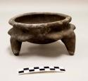 Tripod bowl, conical feet, flared rim, and series of half-circle protrusions encircling the body