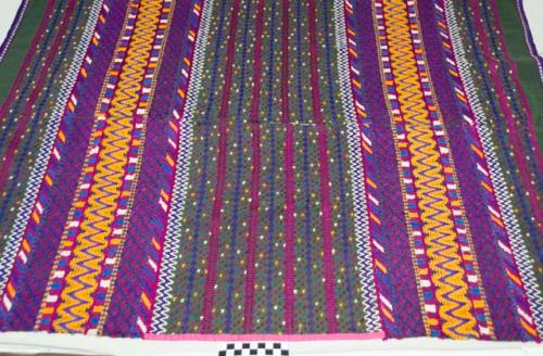 Huipil, woman's shirt, dark green with pink bands at edges, gold, magenta, purple, blue and white geometric designs