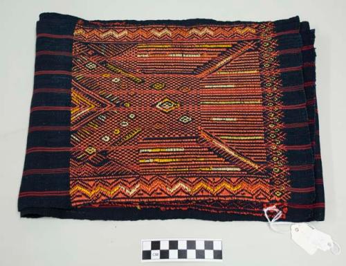 Belt, man's, indigo with red stripes and areas of heavy design at both ends with orange and yellow geometric shapes and double headed eagles