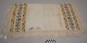 Mantel, table cloth, two pieces, crochet edges, white with two bands of multicolored geometric designs, weaver's initials N.M. in one corner; discolored