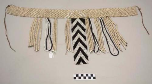 Beaded cache sex; waist band of ostrich eggshell beads with horizontal rows of white glass beads at center; dangling central panel with black and white glass bead chevron pattern; dangling strings of ostrich eggshell beads, black glass beads, or white glass beads are across the front of the skirt