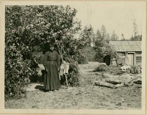 Marie Blucher standing, with house in background