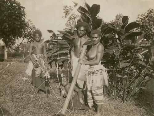 Four natives, one man, two adult women and an adolescent girl by some foliage