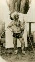 John Bathers in costume of a Thompson River Indian, holding spear and wearing eagle feather headdress