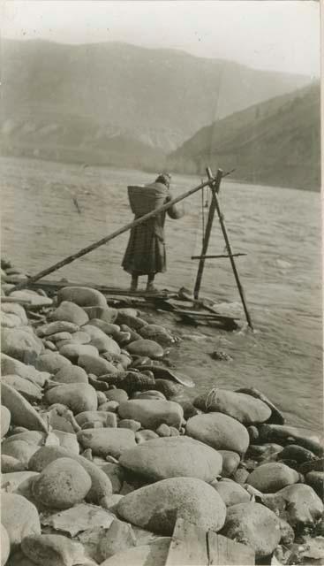 Thompson River Indian woman washing gold in pan along river.