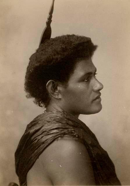 Studio portrait of a Fijian woman, in profile, wearing a comb in her hair