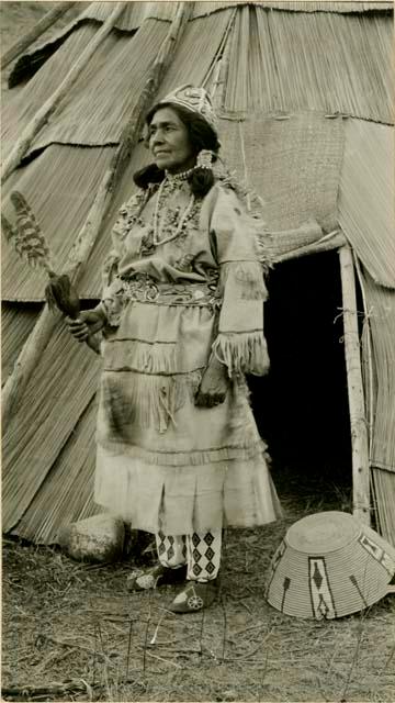 Thompson River Indian woman "KwElEmakst" in costume, in front of tepee