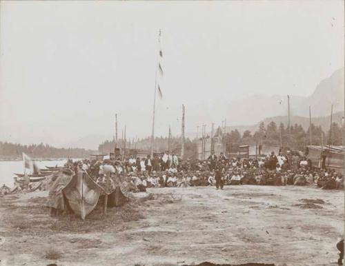 Large groups of people sitting for picture by river encampment