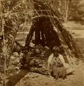 Woman (octogenarian) and child sitting in front of teepee