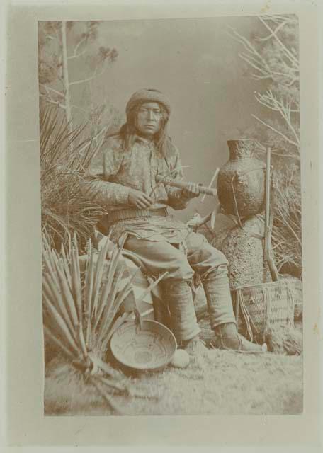 Apache man in a studio-staged scene holding a musical instrument