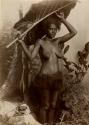 Studio portrait of a Fijian woman posed holding a large leaf over her head