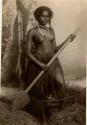 Fijian girl from the reefs, in a studio-staged scene, holding a wooden paddle