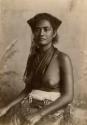 Studio portrait of a Fijian woman wearing fabric around her waist and neck, with bare breasts