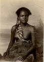 Studio portrait of a Fijian girl, wearing fur over her waist and a fabric sash across her torso