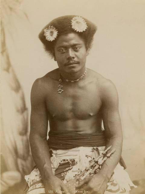 Studio portrait of a Fijian man wearing a beaded choker and flowers in his hair