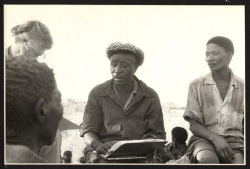 Man being interviewed by Lorna Marshall, with Frederick Geib taking notes, /Gao interpreting