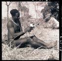 Bela cleaning wart-hog tusks, with tents in the background