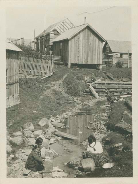Three Makah women washing, Neah Bay, house in background