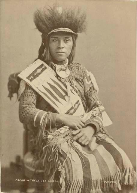 Portrait (Front) of Oscar Mark or Little Vessel in Native Dress with Headdress and Holding Pipe-tomahawk