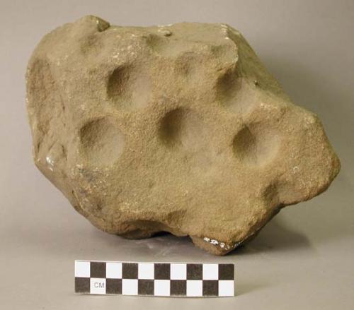 Ground stone object, many large pits