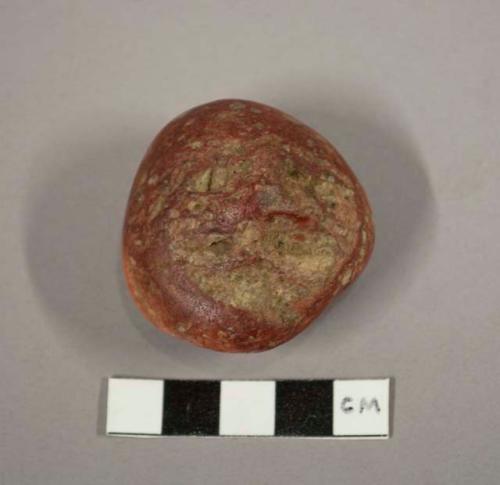 Red stone object - human face on one side