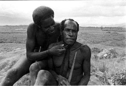 Shot of 2 men; one of them is cutting the other's beard with Robert Gardner's pen knife