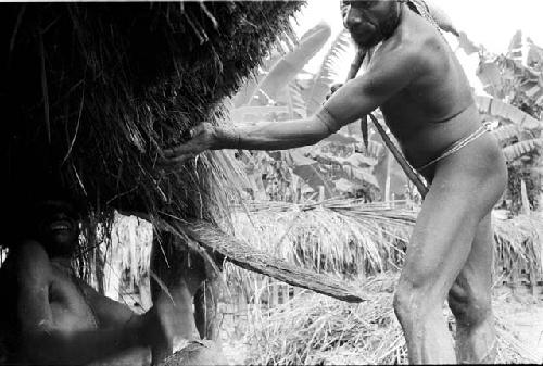 Apeori and other men trimming the grass over the sides of the honai