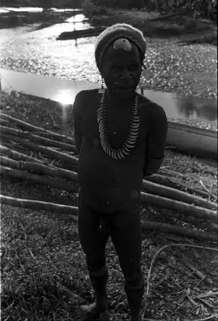 A man standing, wearing a necklace made of some kind of teeth