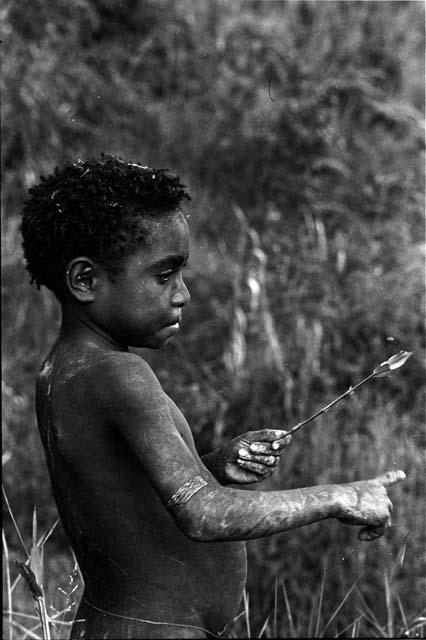 Tukom fixes a grass arrow to throw