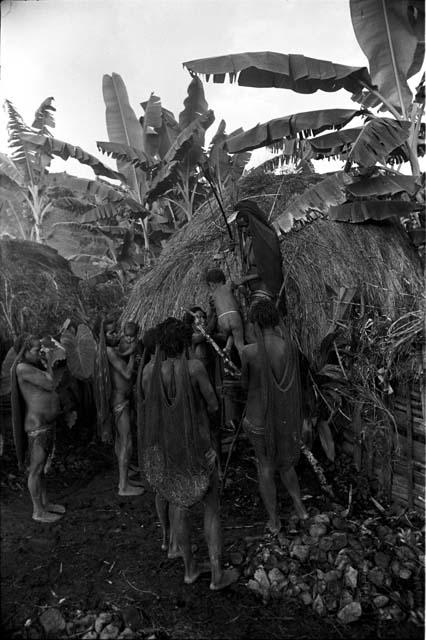 During a healing ceremony, Loliluk's ill wife hands her child down, off of the tripod