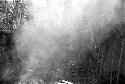 Yoli and Yegé Asuk, shrouded by smoke, repairing the waroleget behind Wali's honai in Wuperainma I