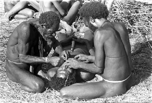 Yoli's beard being picked by Tuessiké and another man