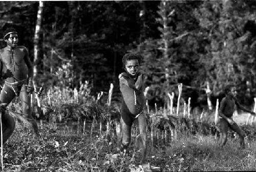 Tukom running towards the camera; Siloba and another boy playing the weem yele