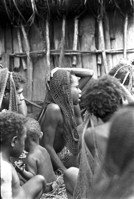 Over the head of Tukom towards a woman who is grieving deeply