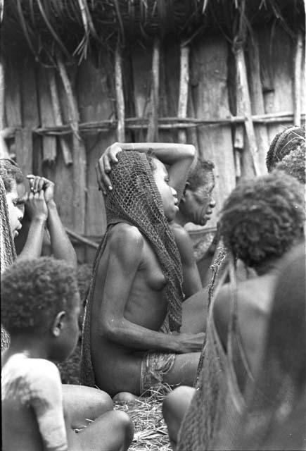 Over the head of Tukom towards a woman who is grieving deeply