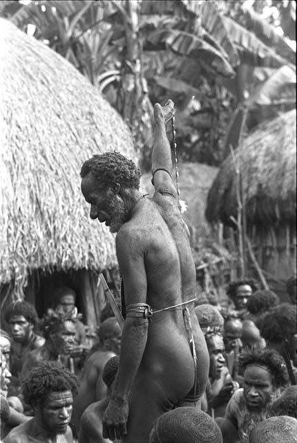 Portrait of Yohonoroik watching procedures at Yonokma's funeral, Aloro in front of him