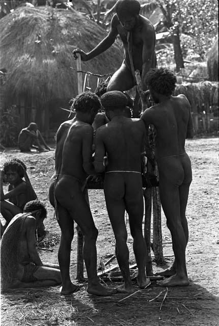 Men arranging Yonokma's corpse on the pia in the early parts of the funeral ceremony