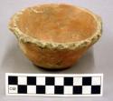 Ceramic bowl with red burnished surface,  scalloped pattern at rim