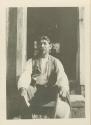 Billy Smithson, seated on stoop, holding his hat in his hand