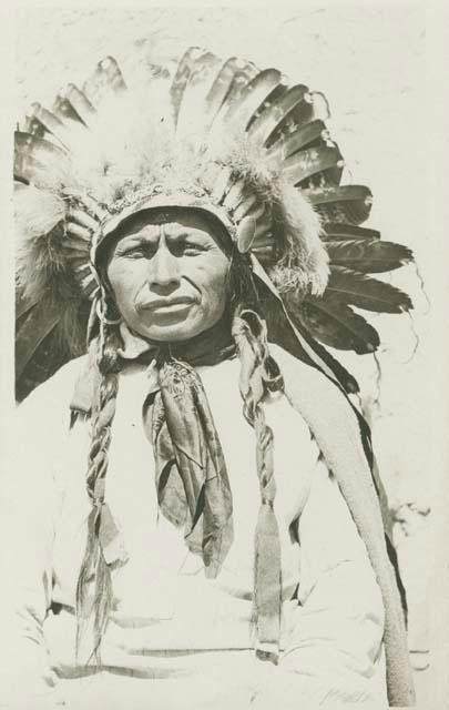 Jicarilla Apache man wearing feather headdress