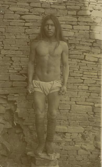 Pablo, a Navajo man, standing in front of an ancient wall