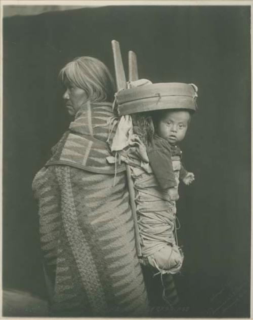Studio Portrait of a woman carrying a baby in a carrier on her back