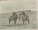 Two Navajo men on horses shake hands