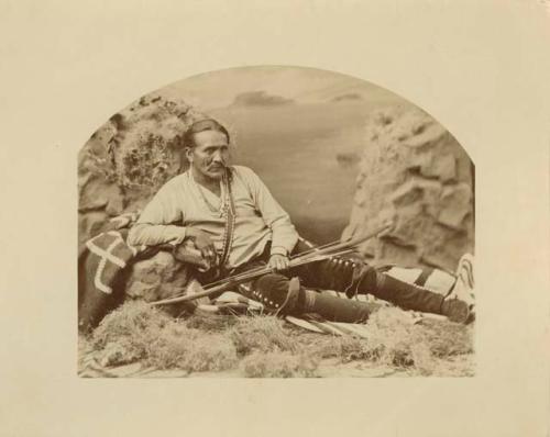 Reclining man with bow and arrows in a studio-staged scene