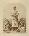 Standing man with fringed shirt and headband