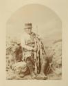Seated man with cap, blanket and boots