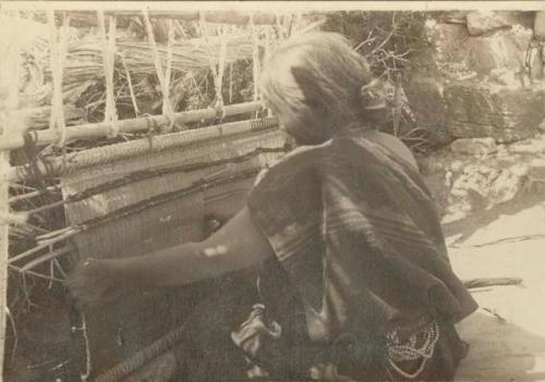 Navajo woman using loom arranged for weaving diagonal cloth