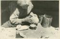 Navajo woman slipping the exterior of a bowl