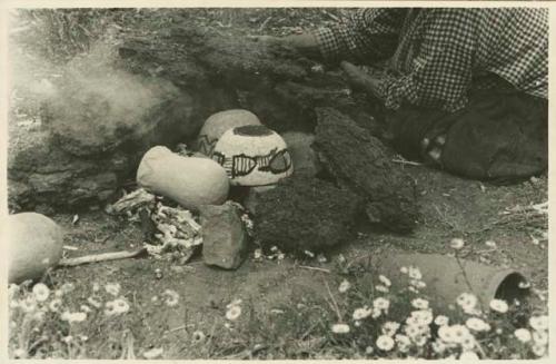 Navajo woman building an oven over the vessels