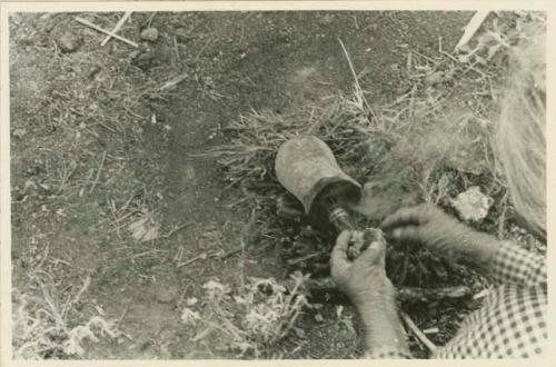 Navajo woman applying piñon gum to a cooking pot after firing